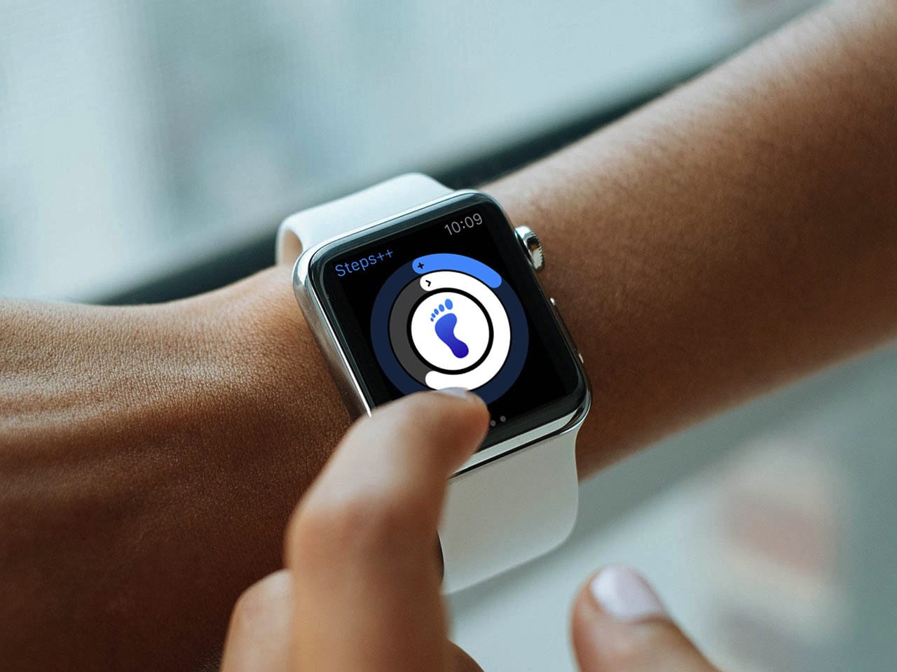 a raised hand showing an apple watch with the steps plus plus app shown on the watch's screen. the app is showing the progress of the wearer's step goals for the day. 
