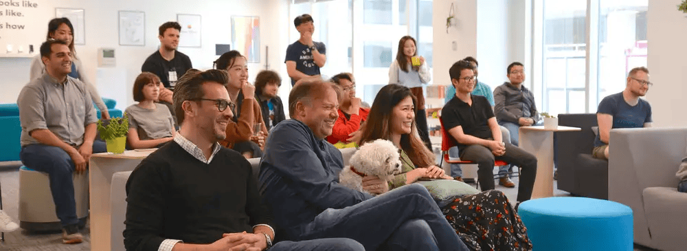 picture of the two tall totems team all sitting together and laughing during a presentation. 